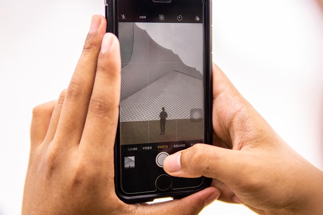 Kota Syahbandar, Melaka - June 26, 2019 : Taking a photo of a model with Encore Melaka building as the background with a smartphone camera.