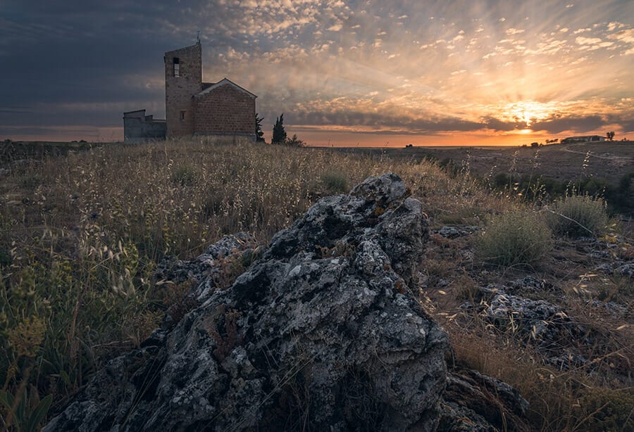 building in background rock in foreground sunset landscape