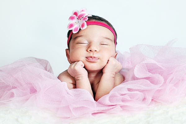 Newborn baby girl posing in tutu skirt and flower head band