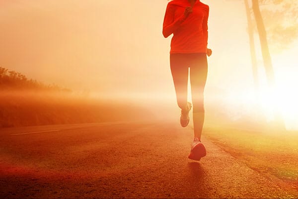 Athlete running on the road in morning sunrise training for marathon and fitness. Healthy active lifestyle latino woman exercising outdoors.